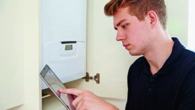 Installateur vor Therme mit Tablet PC
