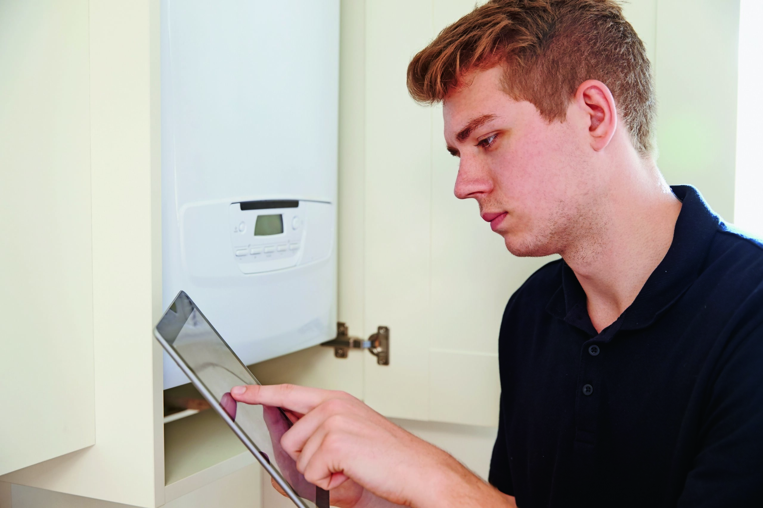 Installateur vor Therme mit Tablet PC