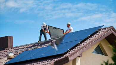 Arbeiter bauen ein Solarmodulsystem auf dem Dach eines Hauses. Installateure tragen Photovoltaik-Solarmodule