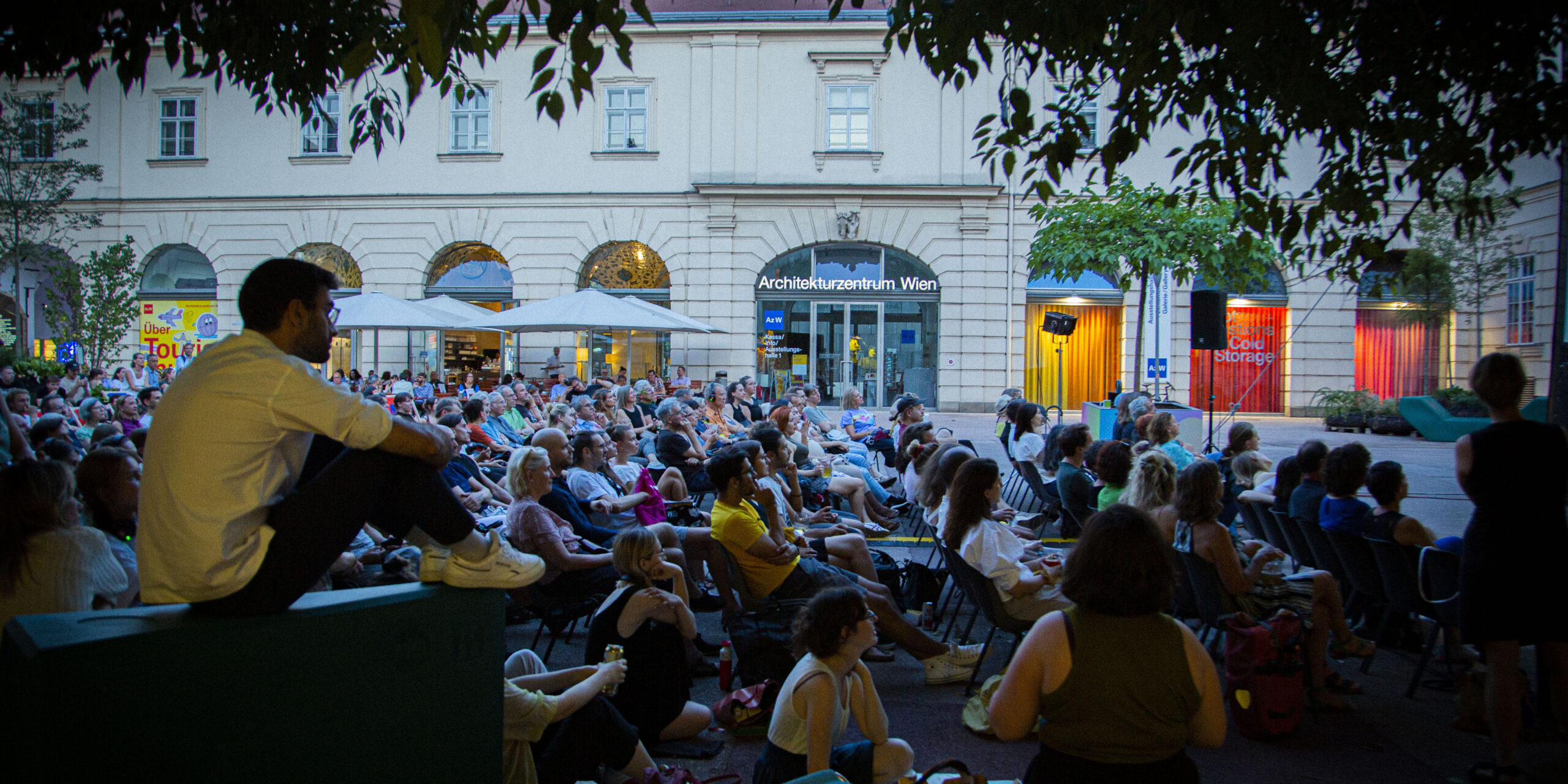 Gäste sitzen abends im Museumsquartier in Wien und schauen einen Film.