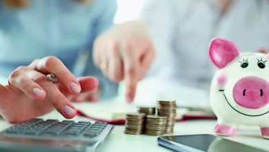 Münzen und ein Sparschwein; Man and woman hand consider on calculator expenses of family budget aganist home background. Lending purchase rental housing mortgage concept