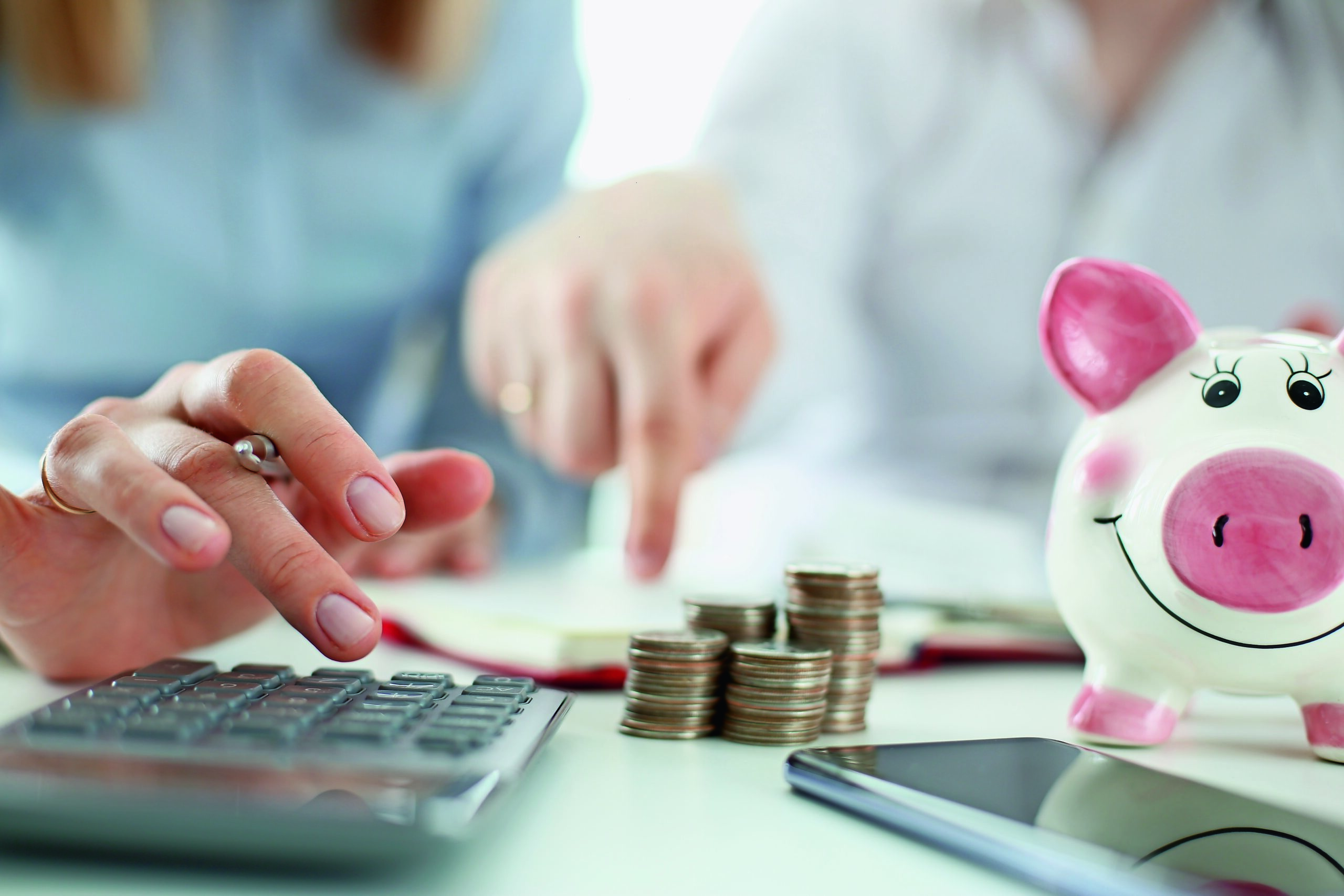 Münzen und ein Sparschwein; Man and woman hand consider on calculator expenses of family budget aganist home background. Lending purchase rental housing mortgage concept