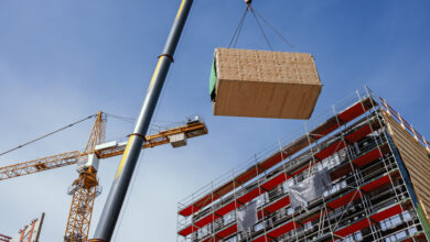 Kran hebt ein vorgefertigtes Holzbaumodul an seine Position in der Struktur. Modulares Bauen.