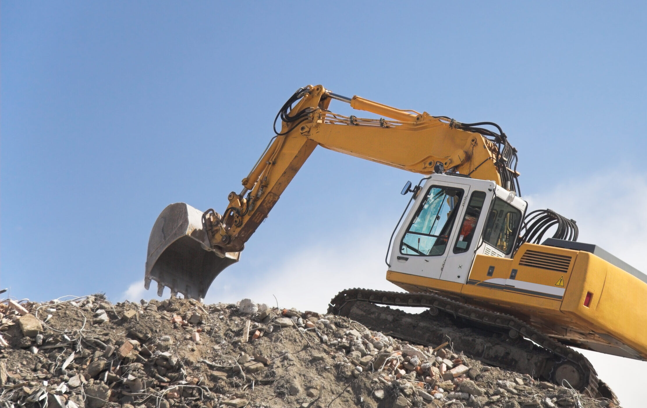 Excavator on a hill of debris