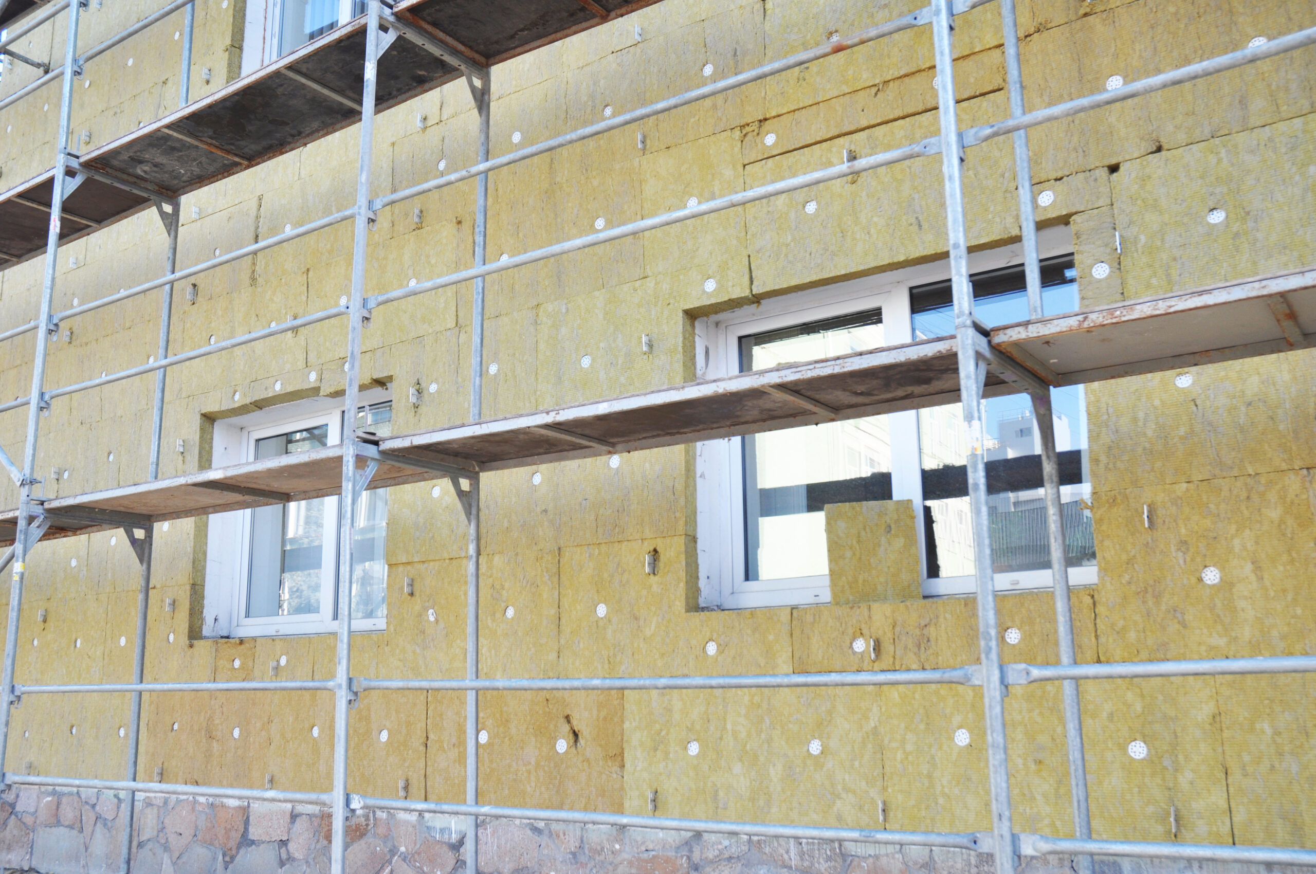 Install Rock Mineral Wool Insulation. Energy efficiency house wall renovation for energy saving. Exterior house wall heat insulation with mineral wool, building under construction.