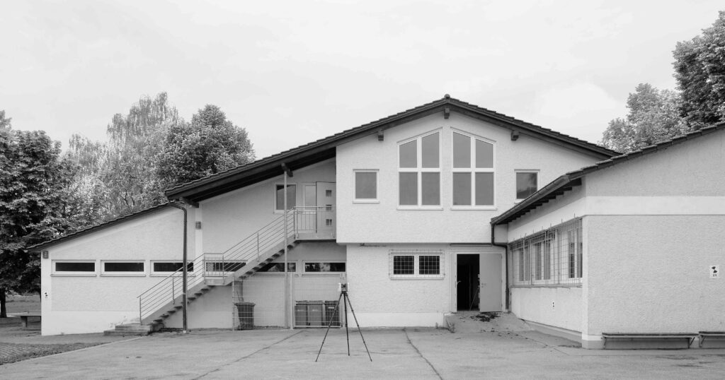 Das Gebäude aus dem Jahr 1964 stammte aus der Feder der Architekten Pfalzer und Schenk. In den Jahrzehnten danach wurde es mehrfach umgebaut und erweitert. Das Bestandhauptgebäude mit langgestrecktem Satteldach wurde zum Großteil abgerissen und machte dem Tragwerk aus Brett-schichtholz-Halbrahmen Platz. © Atelier Kaiser Shen