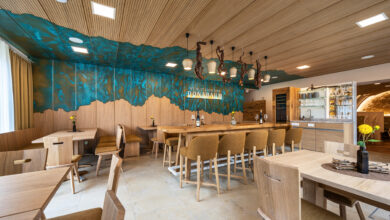 Als Reminiszenz an die Donau schlängelt sich ein metallisch-blau-grünes Band über Wand und Decke des neuen Wintergartens des Weinguts Donabaum. © Obruca Tischlerei & Planung