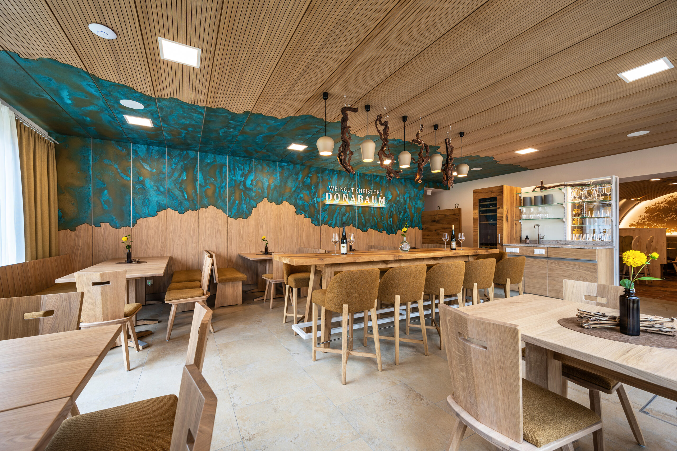 Als Reminiszenz an die Donau schlängelt sich ein metallisch-blau-grünes Band über Wand und Decke des neuen Wintergartens des Weinguts Donabaum. © Obruca Tischlerei & Planung