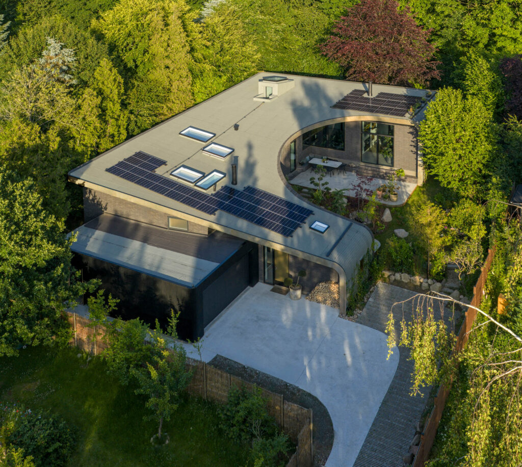 Das u-förmige Haus basiert konzeptionell auf einem geschwungenen Dach, das sich dem Gefälle der Landschaft anpasst und einen geschützten Gartenbereich schafft. © Velux / Adam Mørk
