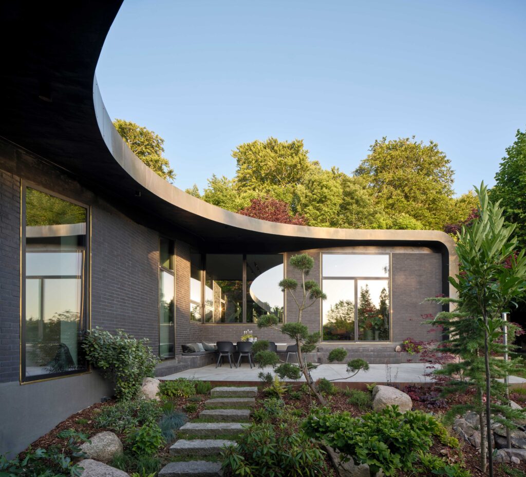 Durch die beiden Flügel des ADA House entsteht ein geschützter Gartenbereich mit Terrasse. Die Form des Grundrisses lässt die Sonne im Verlauf des Tages in weite Teile des Gebäudes einfallen und macht so die Tageszeiten erlebbar. © Velux / Adam Mørk