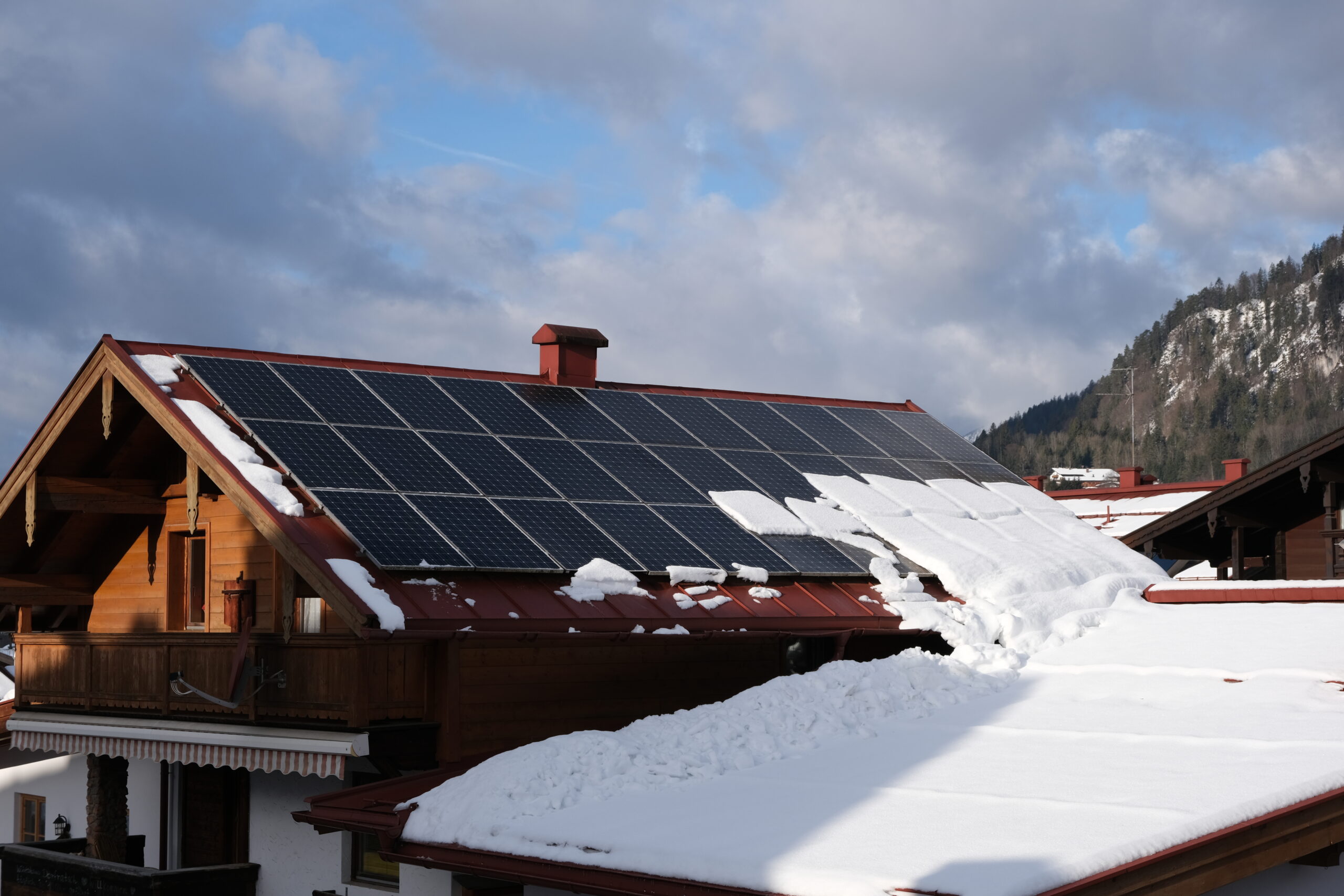 In den Wintermonaten kann die Kombination aus glatten PV-Modulen auf geneigten Dächern und Schneefall dazu führen, dass Schneemassen unkontrolliert abrutschen. Wird das nicht durch entsprechende Schneeschutzmaßnahmen verhindert, können daraus nicht nur wirtschaftliche Schäden entstehen, sondern auch Risiken für Nutzer*innen von Verkehrswegen. © iStock / Getty Images Plus / Sebastian Ohlig