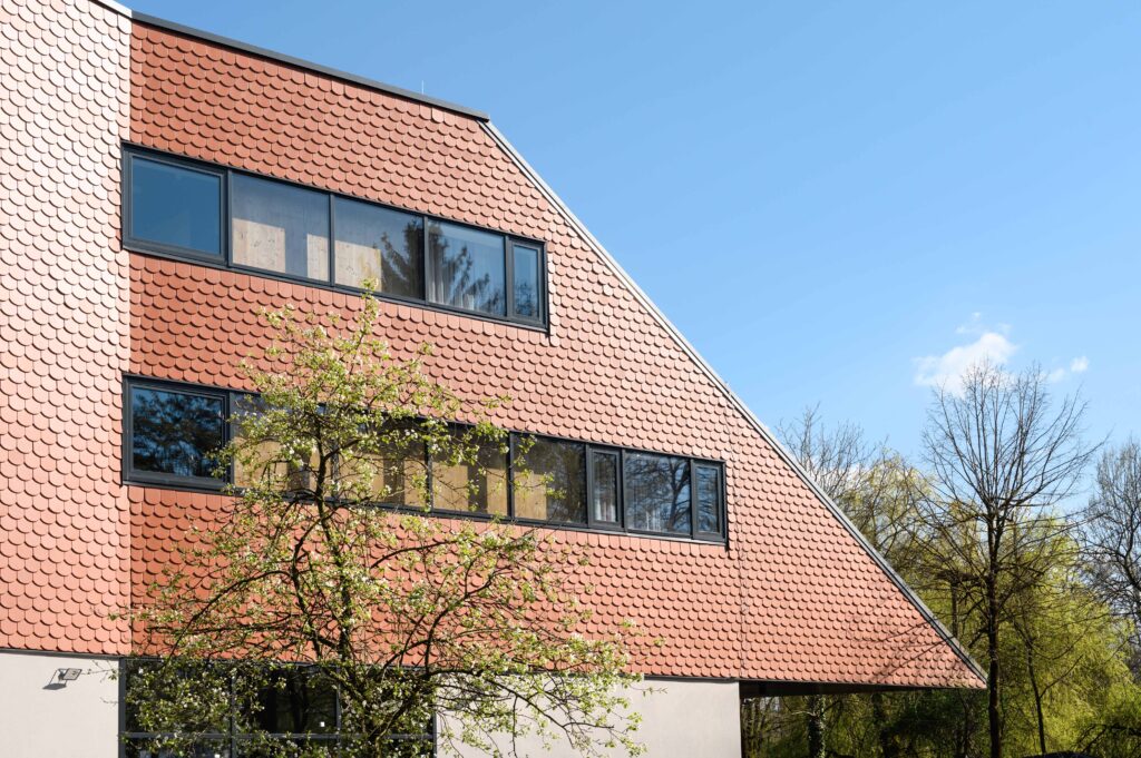 Sowohl das geneigte Dach als auch die hinterlüfteten Fassaden wurden mit für die Region typischen klassischen Tondach Biber-Ziegeln ausgeführt. © Wienerberger d.o.o.
