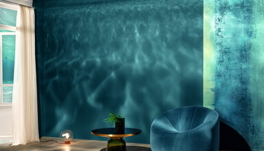 Der warmtonige Holzboden bildet die stabile Basis für das tiefblaue Deep Ocean, das hier von der Spiegeldecke mit und ohne magische Lichtreflektionen aufgenommen wird. Rechts die Oberfläche des Jahres Stucco Eleganza Fusion, bei der Quarzpartikel für eine mineralisch-rau anmutende Haptik und Optik sorgen. © Synthesa