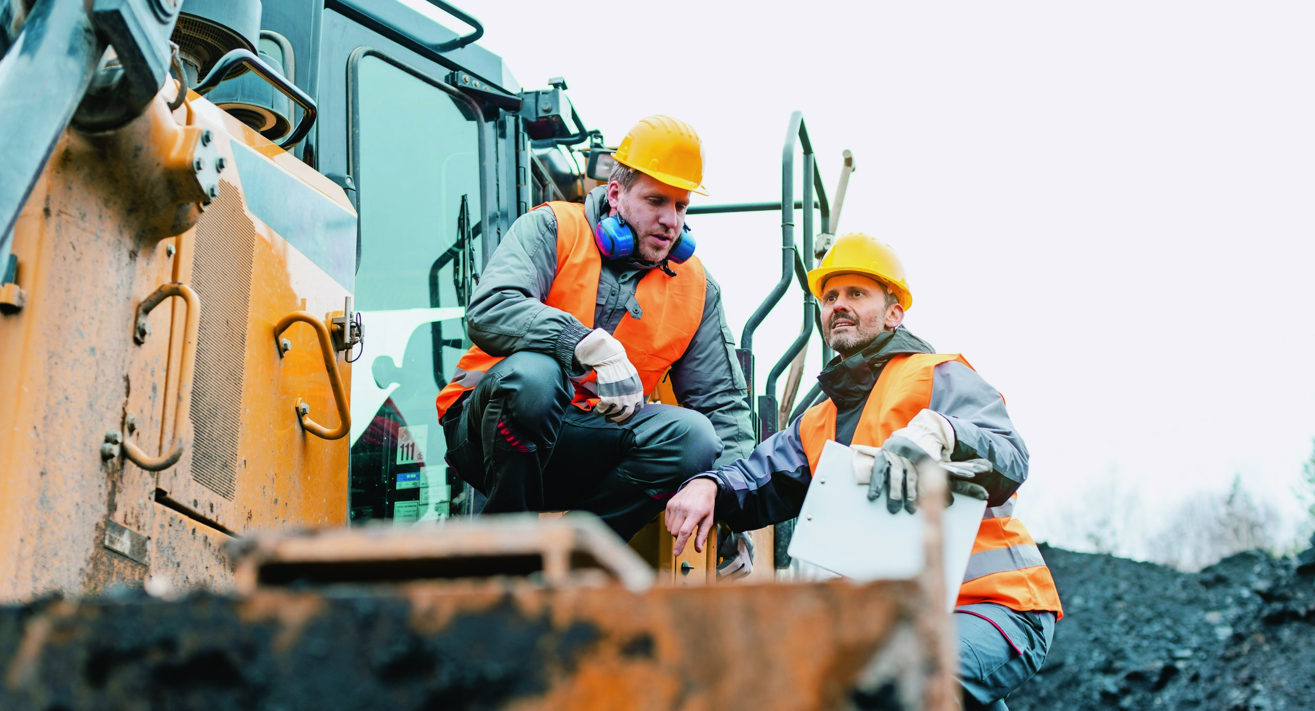 Zwei Bauarbeiter auf einem Baufahrzeug