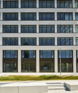 Stützen und Brüstungen sind mit einem hellen Travertin verkleidet. Die Fenster reihen sich zu Fensterbändern und unterstützen die horizontale Struktur. © Olaf Rohl/Saint-Gobain Glass