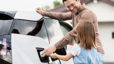 Mann und Kind laden E-Auto auf.