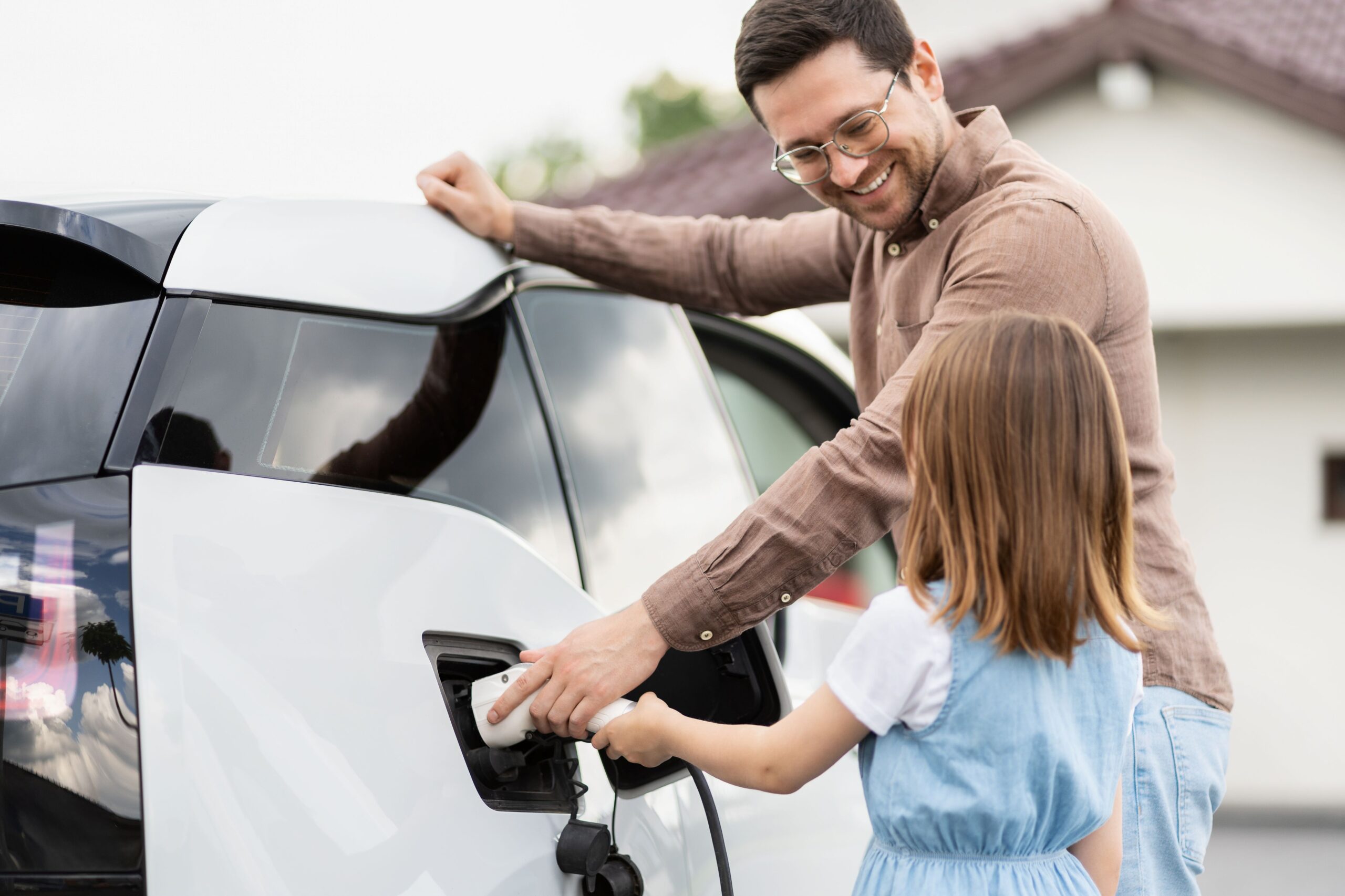 Mann und Kind laden E-Auto auf.