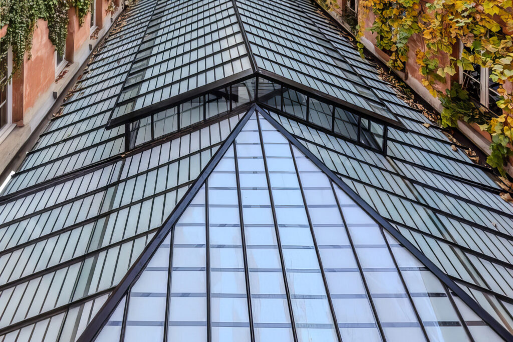 Blick auf das geneigte Glasdach mit seiner filigranen T-Metall-Unterkonstruktion: Die Bestandsprofile konnten erhalten und mit schlankem Fineo-Vakuumisolierglas neu verglast werden – bei minimaler Aufbauhöhe und deutlich verbesserten bauphysikalischen Kennwerten. © Fineo