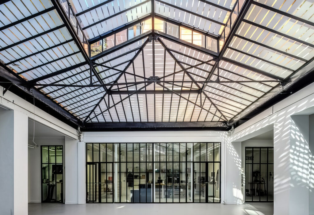 Innenansicht des erneuerten Glasateliers: Die historische Stahlkonstruktion blieb sichtbar und wurde mit vakuumgedämmtem Fineo-Glas ausgestattet. So vereint das Dach filigrane 1930er-Jahre-Ästhetik mit einem Ug-Wert von bis zu 0,7 W/(m²K) und verbessertem Schallschutz. © Fineo