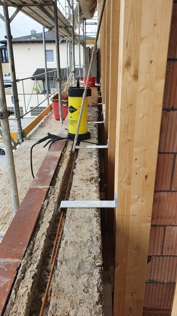 Die Rückverankerung der Stampflehm-Fassadenelemente am Holzskelett erfolgte mittels Z-förmiger Stahlverbinder.