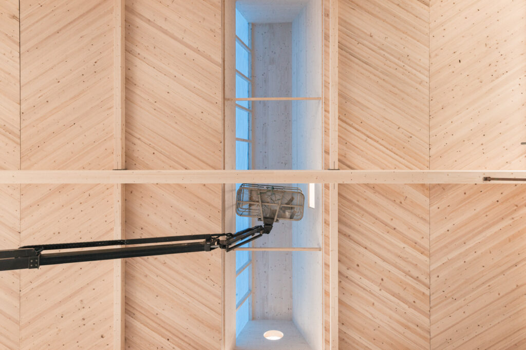 Die Hallendecke mit einem Fischgrät ähnlichen Muster besteht aus leim- und metallfreien, luftdichten massivhölzernen GFM-Platten, die als statisch wirksame Scheibe fungieren.