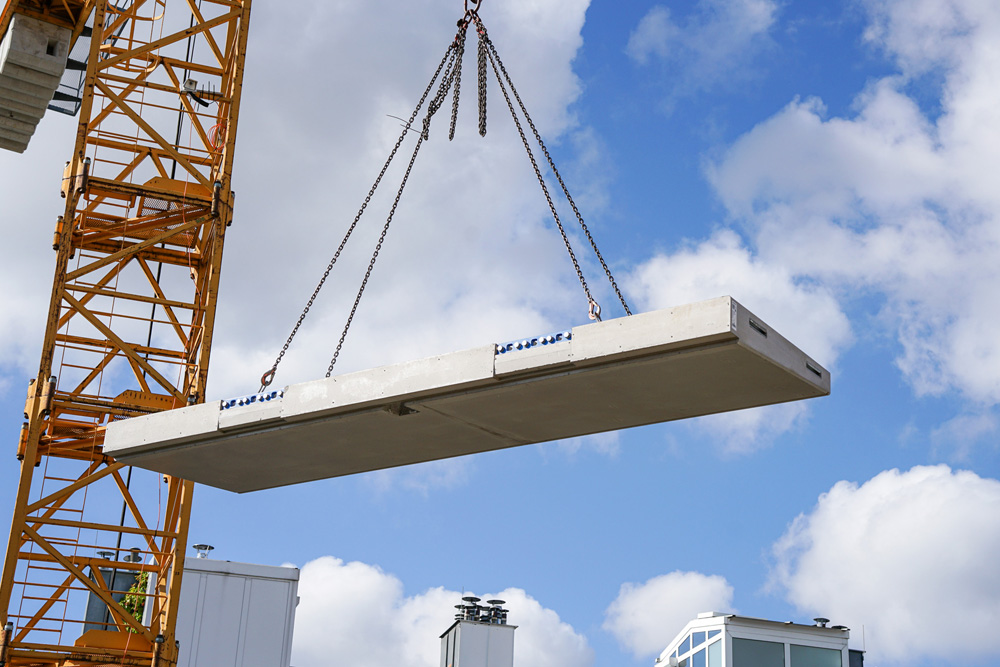 Just-in-time auf der Baustelle: Die Balkonplatte wird als Fertigteil an die Baustelle geliefert und mittels eines Krans zur jeweiligen Anschlussstelle des Gebäudes gehoben. Der deckenseitige Part von Schöck Isokorb IQ Typ K wurde vorab im Gebäude verbaut. Im Bild: Projekt Seidengasse 32 im 7. Wiener Gemeindebezirk der OBENAUF Immobilienentwicklung GmbH. 