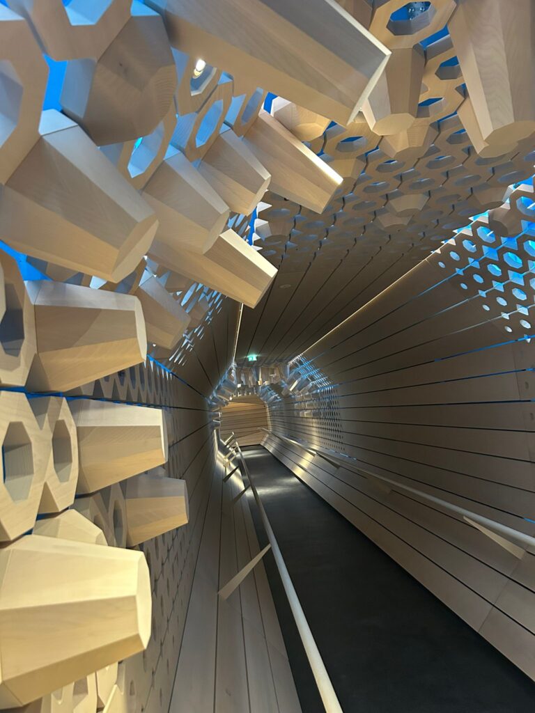 Die Holzmanufaktur und Vitrinenbau Auer aus Innsbruck hat für den Retailtunnel der Swarovski Kristallwelten in Wattens eine außergewöhnliche Wandverkleidung aus vierzig Millimeter starken Eschenholz-Massivbohlen umgesetzt.