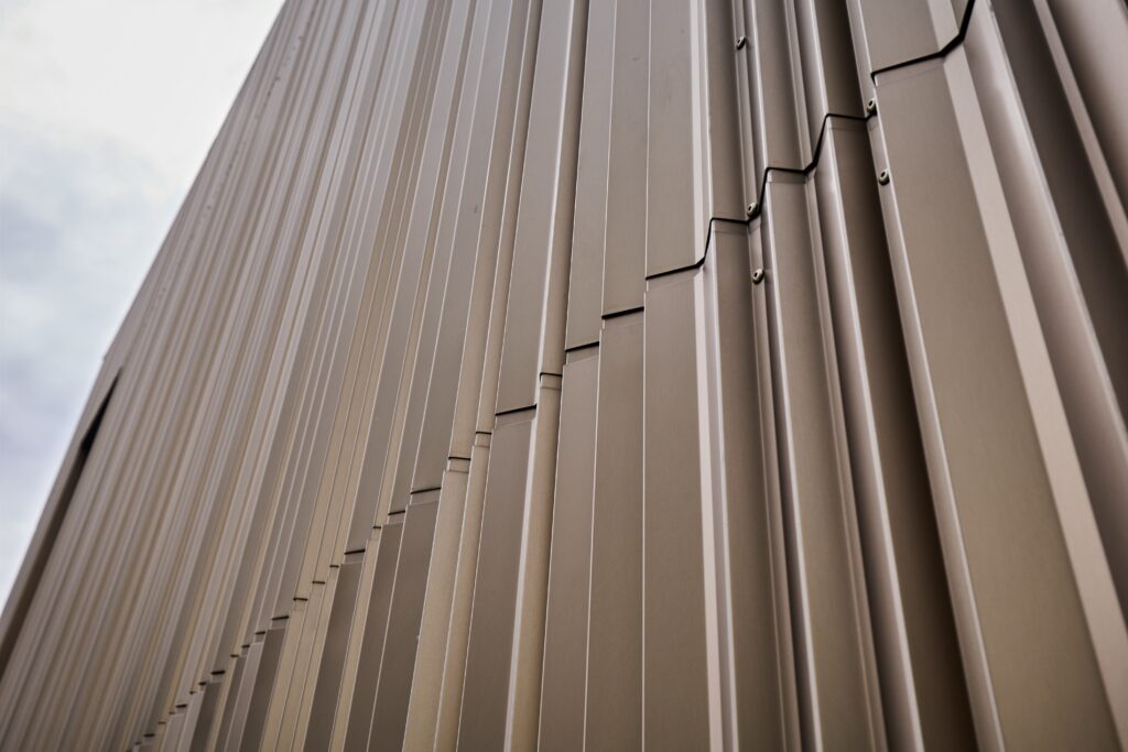 Die gekanteten Aluminiumprofile verleihen dem Gebäude reliefartige Strukturen, klare Linien und ein rhythmisches Fassadenbild.