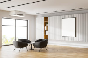 Corner of modern office waiting room with white walls, wooden floor, comfortable grey armchairs near round coffee table, bookshelves and mock up poster. Blurry tropical view. 3d rendering