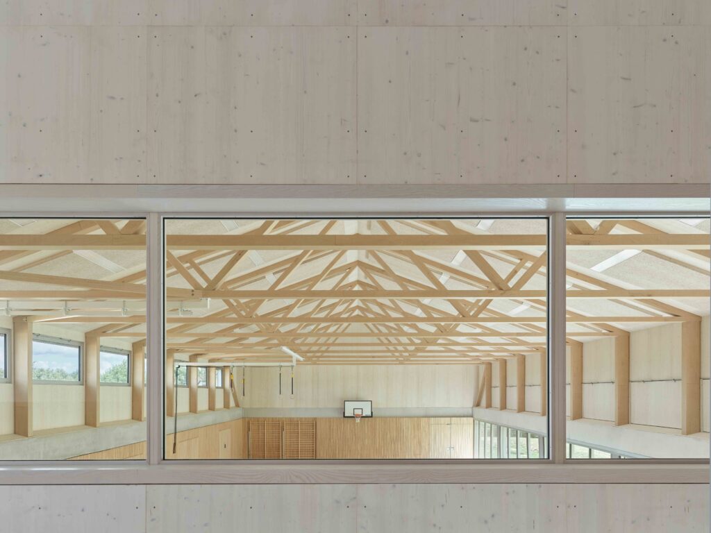 Betritt man das Gebäude im Obergeschoß, fällt der Blick direkt auf die fast ornamental wirkende Dachkonstruktion aus Polonceau-Trägern, die die Sporthalle überspannen.