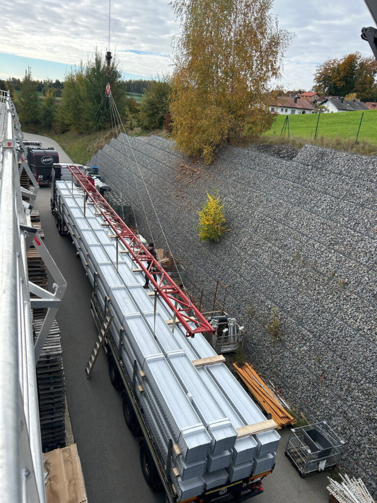 Anlieferung der „Rib-Roof Speed 500“ Profilbahnen: Mithilfe einer Traverse wurden die Bahnen auf die Dachfläche gehoben und für die Montage vorbereitet.