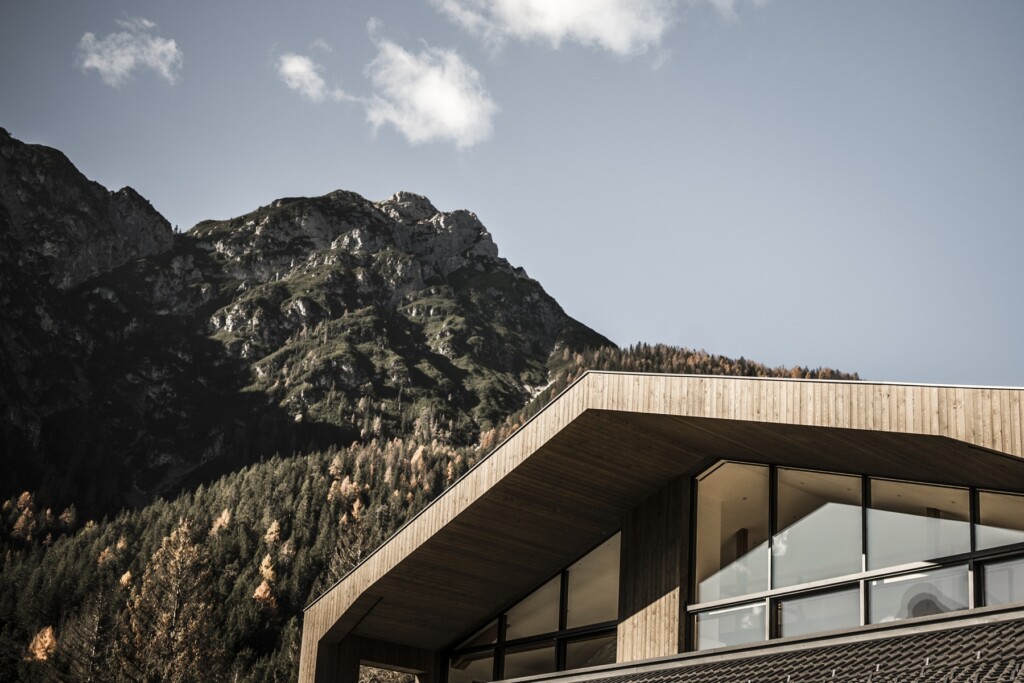 Die Holzfassade fügt sich harmonisch in die alpine Landschaft ein. Großzügige Glasflächen schaffen einen modernen Ausdruck.