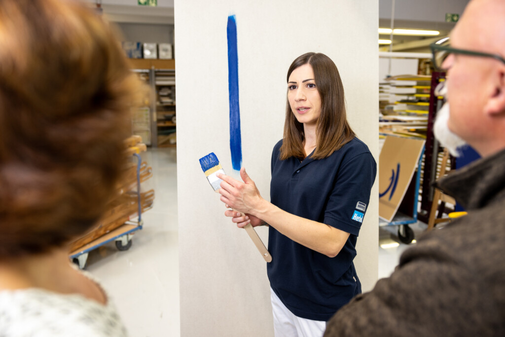 Perfekte Verarbeitung: Anwendungstechnikerin Dajana Möhlenkamp demonstriert, wie sich Innenwandfarben mit dem Pinsel sauber und präzise beschneiden lassen. Die Vorführung verdeutlicht zugleich die hohe Ergiebigkeit – ein wesentliches Qualitätsmerkmal der Produkte von Sikkens und Herbol.